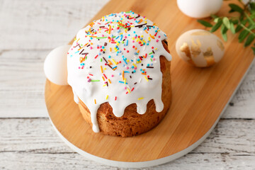 Board with tasty Easter cake on white wooden background