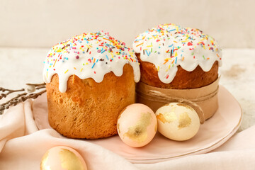 Plate with delicious Easter cakes and eggs on light background