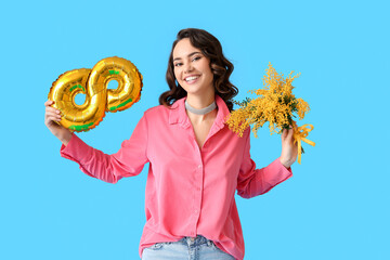 Young woman with mimosa flowers and balloon in shape of figure 8 on blue background. International...