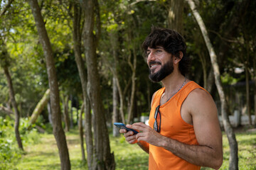 Young man at a park on a beautiful sunny day with mobile phone.