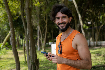 Young man at a park on a beautiful sunny day with mobile phone.