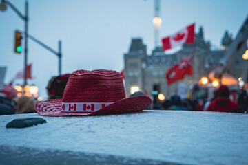 Red hat in front of Canadian flags.