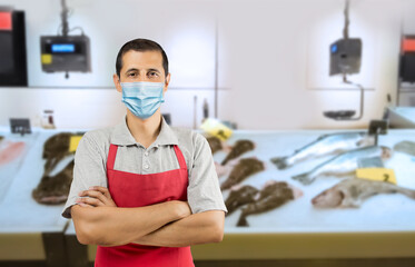 Fototapeta na wymiar Fishmonger wearing a mask and looking at the camera with his arms crossed