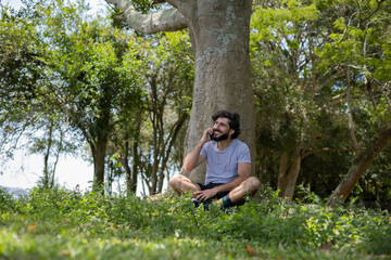 Young man at a park on a beautiful sunny day with mobile phone.