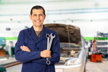 Image of a male mechanic standing confidently while holding two spanner
