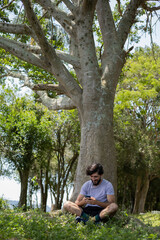 Young man at a park on a beautiful sunny day with mobile phone.