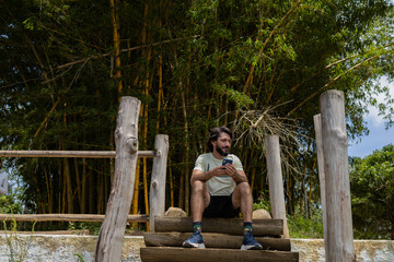 Young man at a park on a beautiful sunny day with mobile phone.