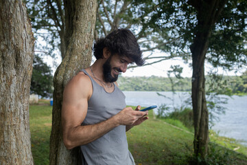 Young man at a park on a beautiful sunny day with mobile phone.