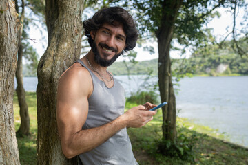 Young man at a park on a beautiful sunny day with mobile phone.