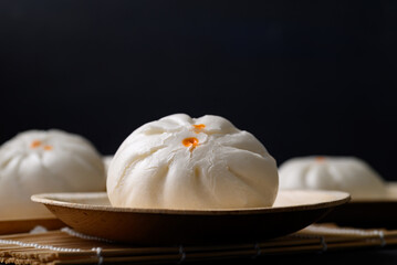 Steamed Chinese bun stuffed with minced pork, egg yolk or sweet on natural plate with black...