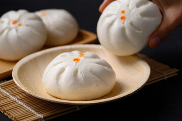 Steamed Chinese bun stuffed with minced pork, egg yolk or sweet on natural plate, Asian food