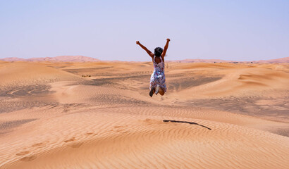 Fototapeta na wymiar Brunette woman jumping happily in the desert