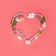 Heart-shaped copying space decorated with various real flowers. Spring concept on a pastel...