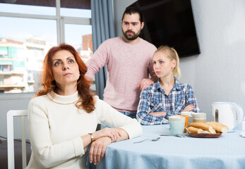 Portrait of sad mature woman sitting after conflict with adult children in home interior