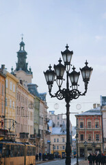 Fototapeta na wymiar Big old curly black vintage lantern in the historical center of Lviv against the blue sky. Winter city concept.