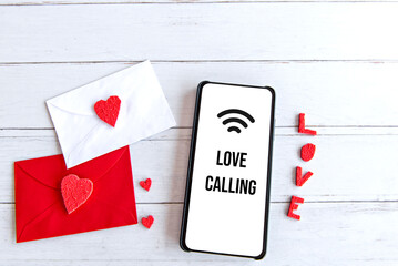Valentine's day concept, love letter and cellphone with white screen on wooden table.