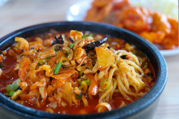 Spicy seafood noodles with various ingredients are provided in the earthen pot.