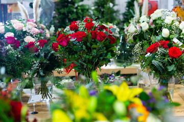 Bouquets of flowers in glassy vases in showroom of floral shop.