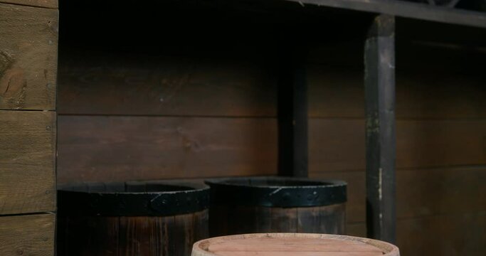 Funny black dachshund dressed as pirate with cocked hat and eyepatch put paws on wooden barrel with rum IN cabin of ship