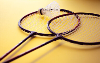 feathers and badminton rackets on a yellow background