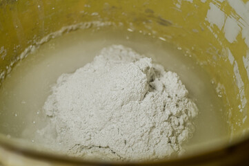 White plaster in a bucket of water. Preparation of mixture for finishing walls and ceilings in the apartment. Repair in the house. DIY. Selective focus