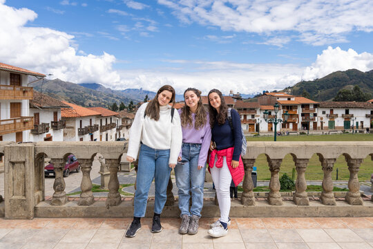 Three young latina women posing on a bridge of a traditional andean town