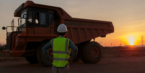 Coal truck drivers in the coal mine stand to watch the sunset.