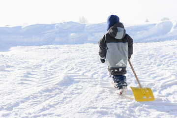Fototapeta na wymiar Four year old boy with a snow shovel gets to work