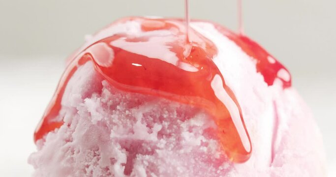 Close-up strawberry sauce flows on top ice cream. Liquid ice cream for decorating food. Food concept.