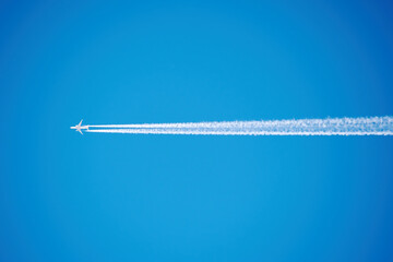 A small passenger plane high in the sky, along with a white trail. Transportation and holidays...