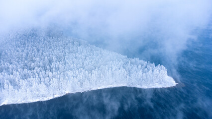 Panoramic aerial view of the winter snow covered forest island and frozen lake from above © useful pictures