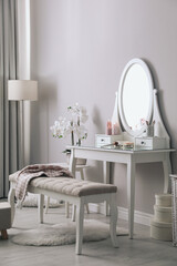 Wooden dressing table with decorative elements and makeup products in room. Interior design