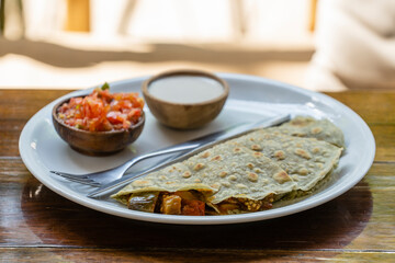 Quesadillas from spiruline tortilla with cashew cheese, eggplant, tomatoes and sour cream and tomato salsa