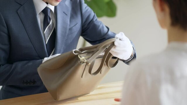 60p　バッグを査定する鑑定士と客