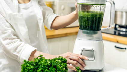Healthy woman enjoy making green vegetables detox cleanse and green fruit smoothie with blender in kitchen at home.dieting concept.healthy lifestyle
