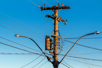 Many wires attached to the electric pole, the chaos of cables and wires on an electric pole, blue...