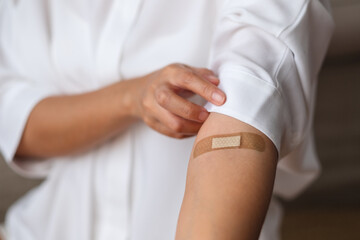 Closeup image of a woman with adhesive bandage, medical plaster, band aid on her arm