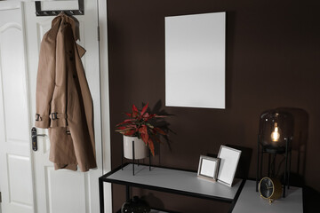 Obraz na płótnie Canvas Stylish hallway interior with empty canvas on brown wall. Mockup for design