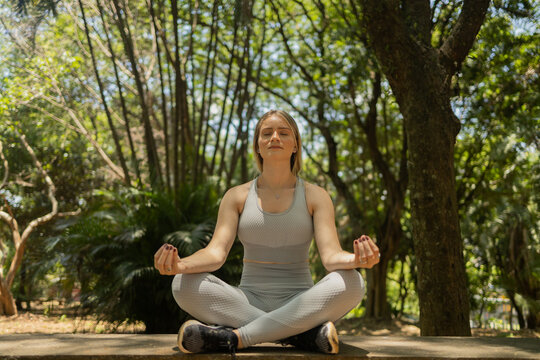 young woman meditating. practice of yoga and meditation on a sunny. day at a park. High quality photo.