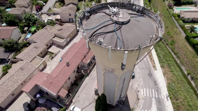 Water tower in Gignac France, with cellular equipment and cables, Aerial orbit around high shot