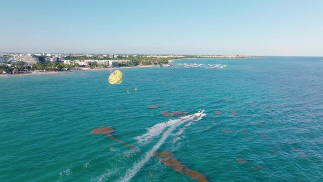 Person parasail dragged by motorboat in Playa Del Carmen bay - aerial tracking