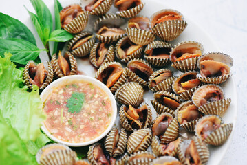 Peeled cockles with seafood sauce and vegetable salad lettuce on plate  background, Fresh raw shellfish blood cockle ocean gourmet seafood in the restaurant, sea shells food