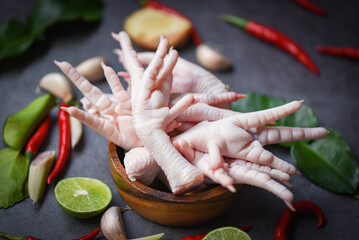 chicken feet on wooden bowl with herbs and spices lemon chili garlic kaffir lime leaves lemon grass, Fresh raw chicken feet for cooked food soup on the dark table kitchen background - 485965147