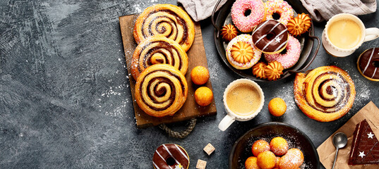 Table with various cookies, donuts, cakes and coffe cups