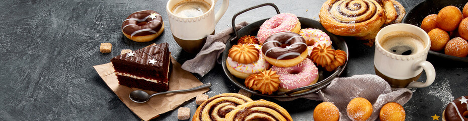 Table with various cookies, donuts, cakes and coffe cups
