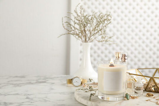 Composition with burning soy candle on white marble table, space for text