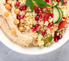Bulgur and hummus salad on light background.