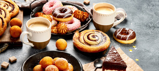Table with various cookies, donuts, cakes and coffe cups