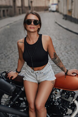 Fototapeta na wymiar Stylish woman posing with retro bike against cityscape in town