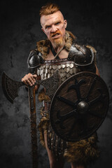 Obraz na płótnie Canvas Scandinavian barbarian with shield and axe against dark background
